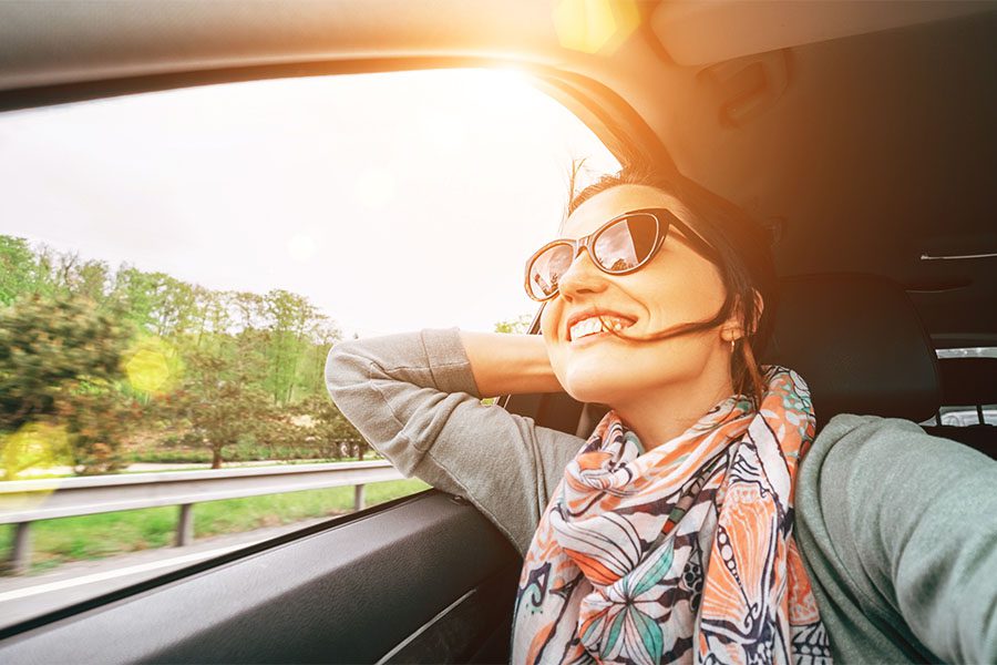 Insurance Quote - View of Joyful Woman Looking Out the Window During a Road Trip on a Sunny Day